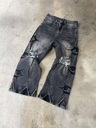 Wide-leg black denim with unique DTG print and distressed detailing, showcasing stylish design and modern fashion.